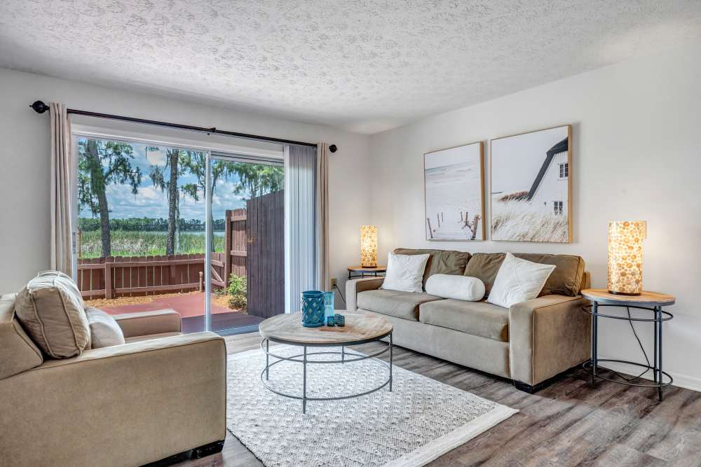 Living room with large couch with coffee table and access to patio at Carlton Arms Of Ocala in Ocala, Florida