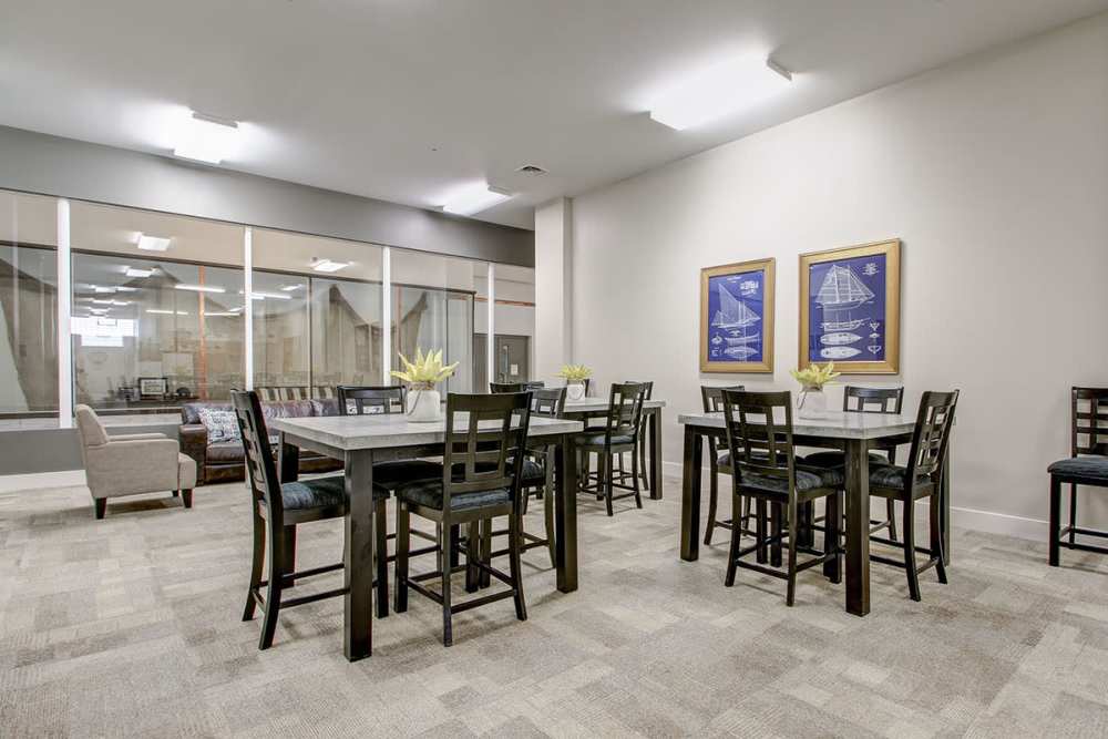 Modern community lounge with tables, chairs, and decorative artwork on the walls at Lloyd House I in Menominee, Michigan