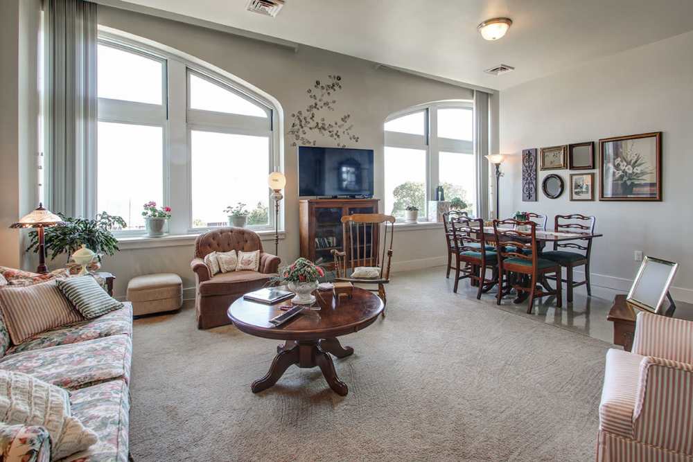 Bright living area with large windows, cozy seating, and dining table for six at Lloyd House I in Menominee, Michigan