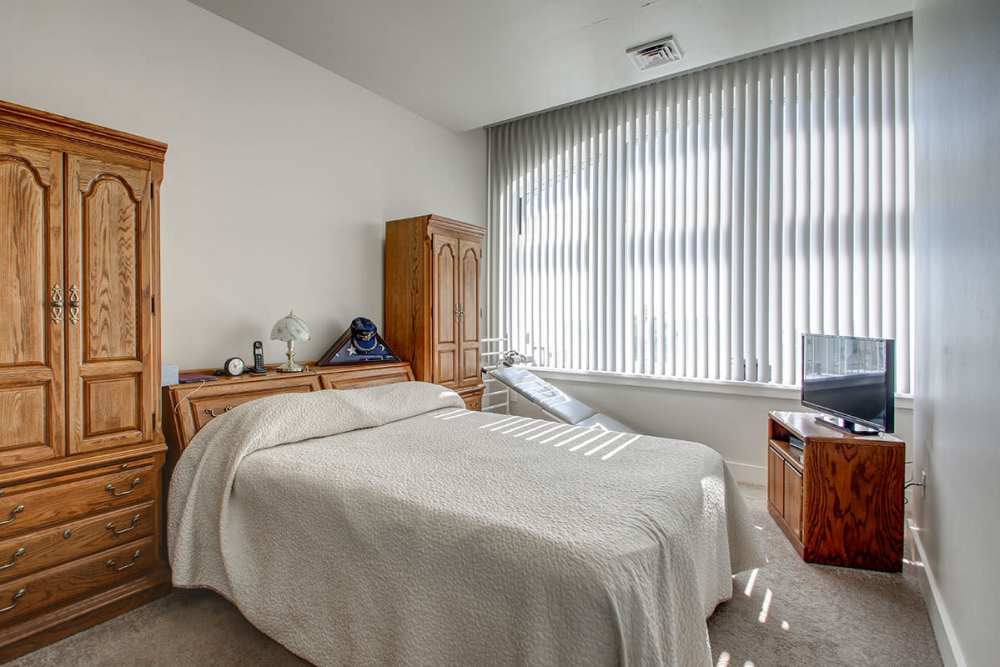 Cozy bedroom with a queen bed, wooden furniture, and large windows with blinds at Lloyd House I in Menominee, Michigan