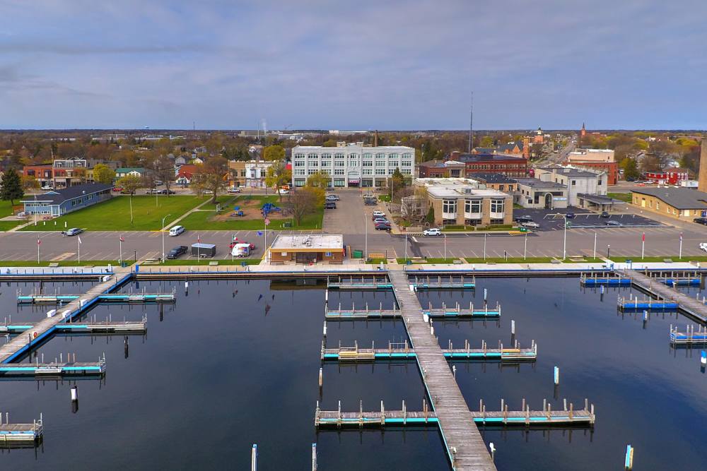 Aerial view of a marina with docks, boats, and nearby buildings and green spaces at Lloyd House I in Menominee, Michigan