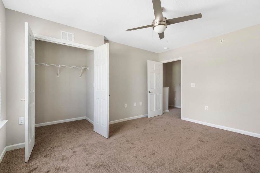 Spacious bedroom with carpeted flooring, ceiling fan, and two open closet doors at Ravenwood Crossing in Rocky Mount, North Carolina