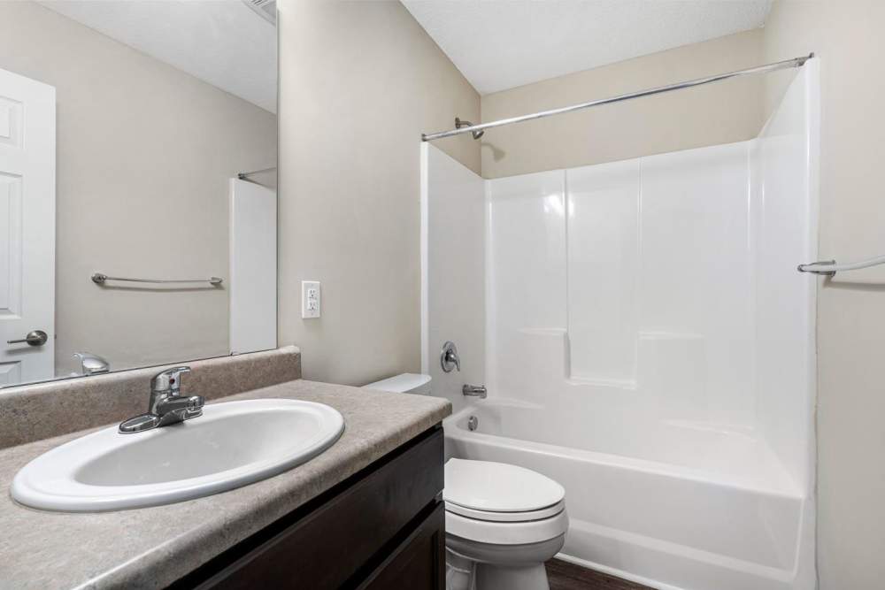 Bright bathroom with a white tub, dark wood vanity, and modern fixtures at Ravenwood Crossing in Rocky Mount, North Carolina