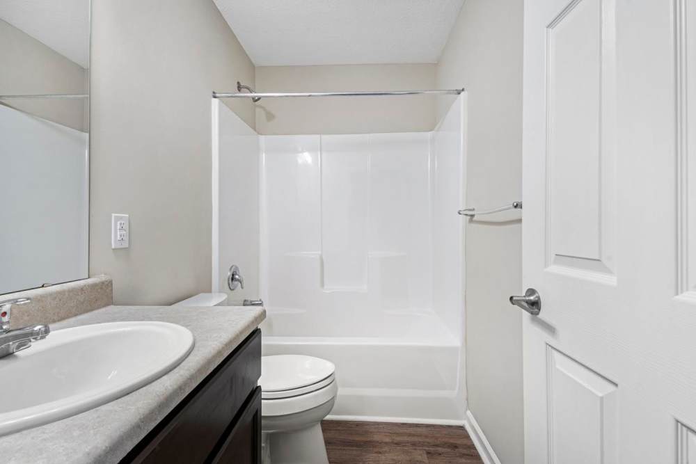 Modern bathroom with a white tub, dark cabinetry, and a large mirror at Ravenwood Crossing in Rocky Mount, North Carolina