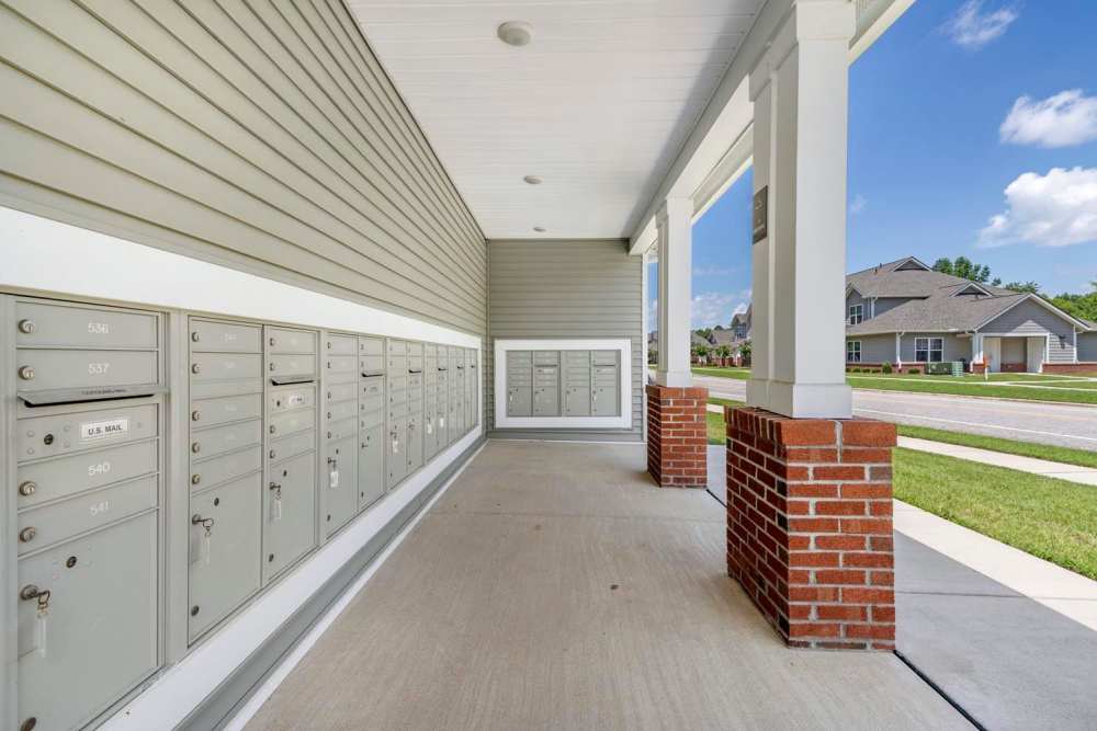 Covered mail area with multiple mailboxes and brick columns, well-maintained sidewalk and green lawn at Ravenwood Crossing in Rocky Mount, North Carolina