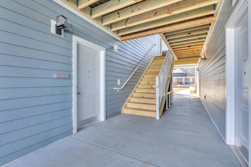 Brightly lit entrance with wooden stairs and blue siding at Rivergate Greene in Charlotte, North Carolina