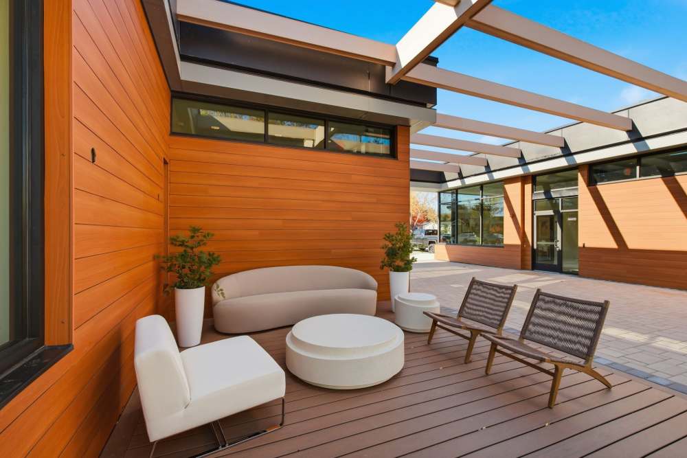Outdoor patio seating area with modern furniture and wood siding at Eagle Rock Apartments at Woodbury in Woodbury, New York