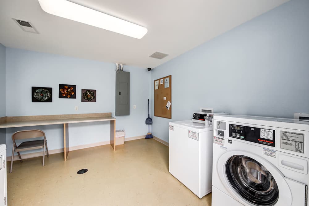 Laundry room with washers, dryers, and folding table at Crowfield Greene in Goose Creek, South Carolina