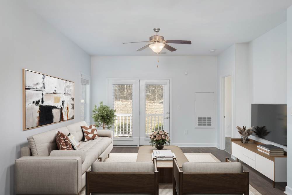 Bright living room with modern furniture, ceiling fan, and access to a private balcony at Crystal Lake & Kingsley Apartments and Townhomes in Fayetteville, North Carolina