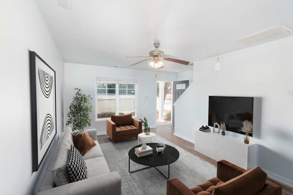Bright living room with wood-style flooring, modern furniture, and large windows for natural light at Crystal Lake & Kingsley Apartments and Townhomes in Fayetteville, North Carolina