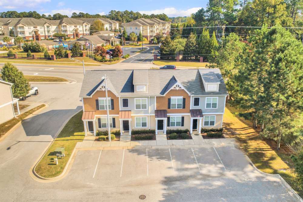 Two-story apartment building with landscaped entrance and parking area, surrounded by trees and greenery at Crystal Lake & Kingsley Apartments and Townhomes in Fayetteville, North Carolina