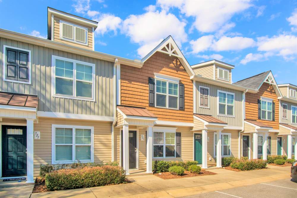 Colorful apartment exteriors with landscaped shrubs and clear blue sky at Crystal Lake & Kingsley Apartments and Townhomes in Fayetteville, North Carolina