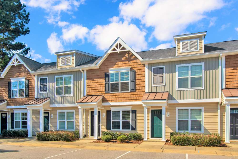 Charming apartment community with modern exteriors and landscaped entryways under a bright blue sky at Crystal Lake & Kingsley Apartments and Townhomes in Fayetteville, North Carolina