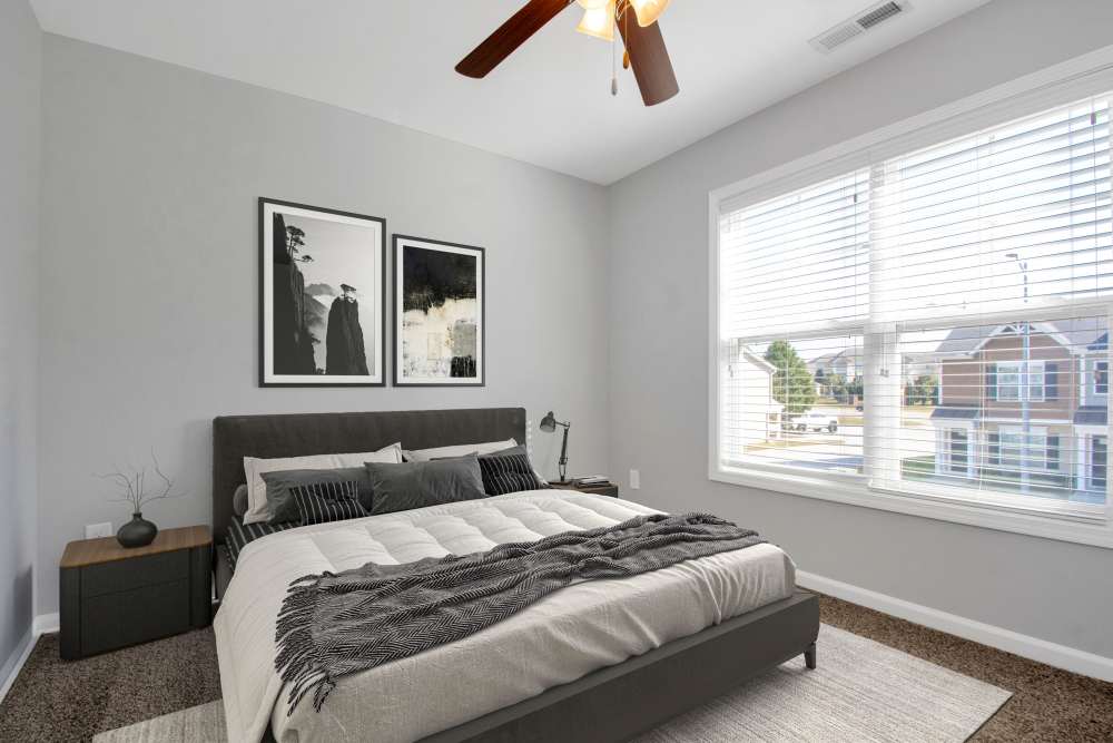 Cozy bedroom with a queen bed, modern decor, and large windows for natural light at Crystal Lake & Kingsley Apartments and Townhomes in Fayetteville, North Carolina