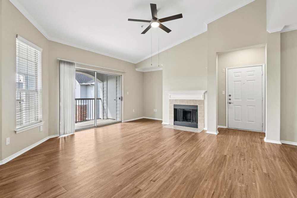 Unfurnished spacious living room with fireplace and open-concept living into kitchen area at Breckinridge Point Apartments in Richardson, Texas