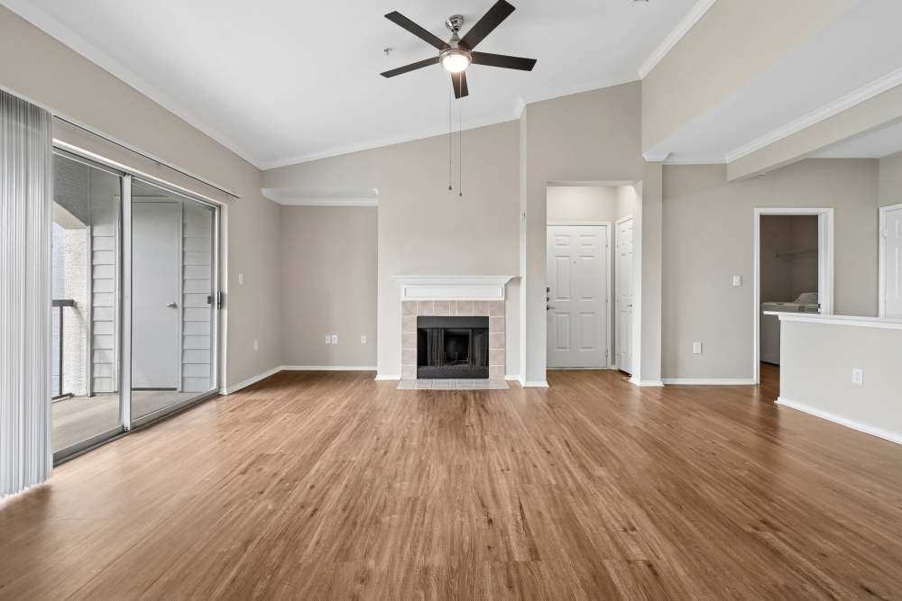 Unfurnished spacious living room with fireplace and open-concept living into kitchen area at Breckinridge Point Apartments in Richardson, Texas