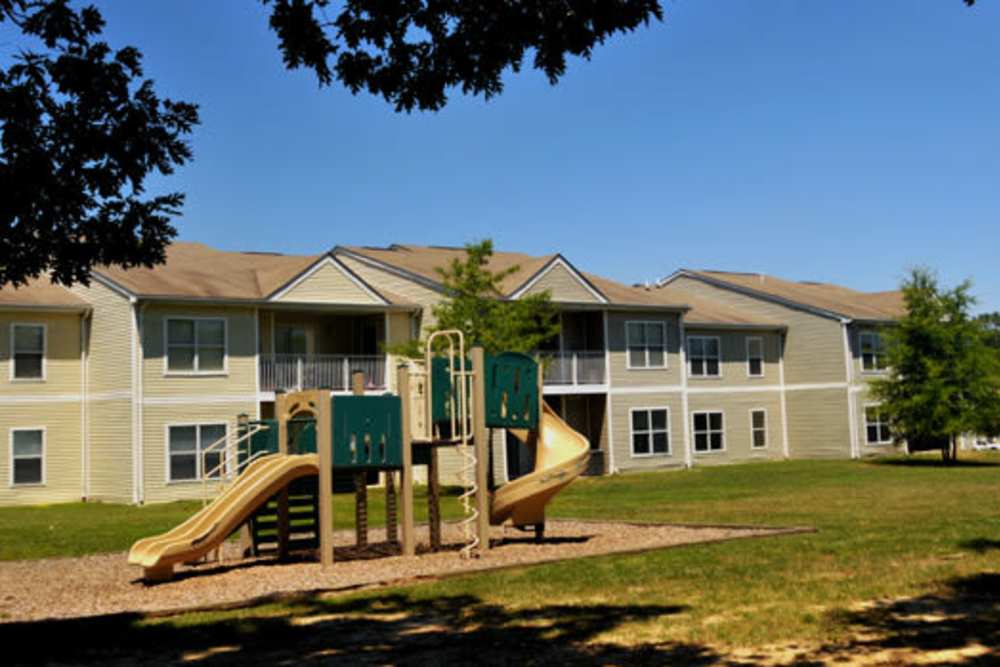Apartment community with playground, grassy area, and balconies under clear blue sky at Spring Valley Apartments in Lexington Park, Maryland