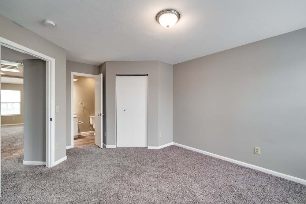 Carpeted bedroom with closet, ceiling light, and bathroom access at Ashton Glen in Centerville, Ohio