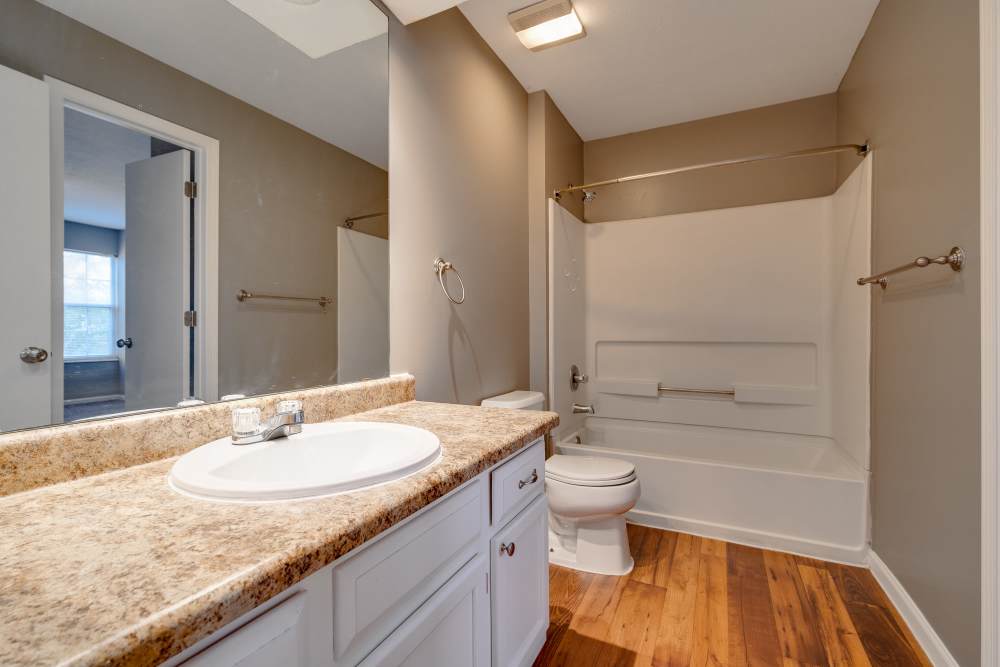 Bathroom with tub shower, toilet, vanity, and wood-style flooring at Ashton Glen in Centerville, Ohio