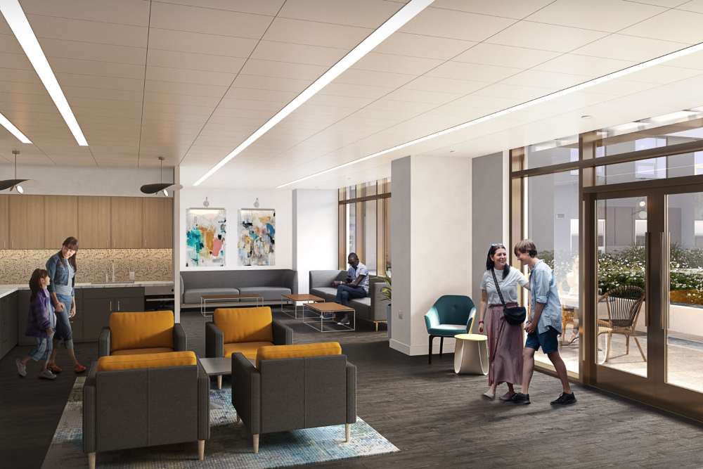Active clubroom at The Exchange at Spring Hill Station with residents, seating areas, kitchen space, and access to outdoor terrace