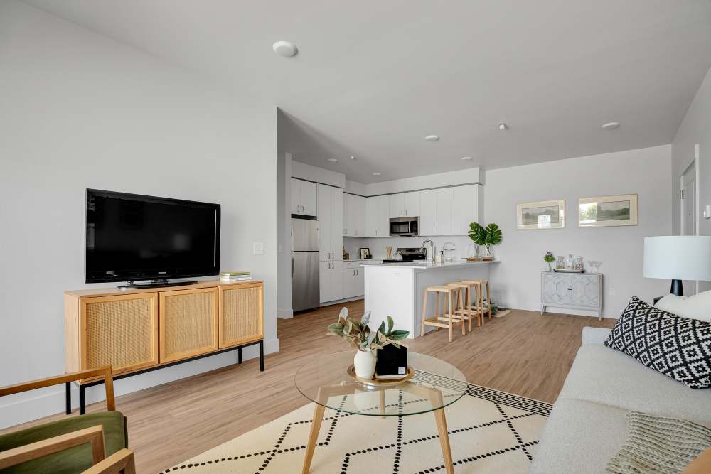 Open layout living area with wood-style flooring, modern kitchen, and stylish furnishings at Tilian Point in Woodburn, Oregon
