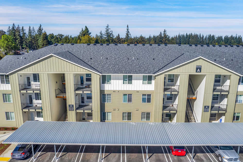 Modern apartment community with covered parking and balconies, surrounded by trees and greenery at Tilian Point in Woodburn, Oregon