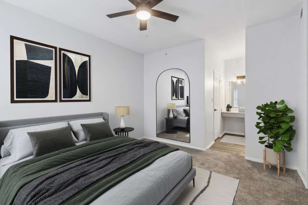 Staged bedroom with upholstered bed, ceiling fan, wall art, full‑length mirror, and vanity area at 530 Buckingham in Richardson, Texas