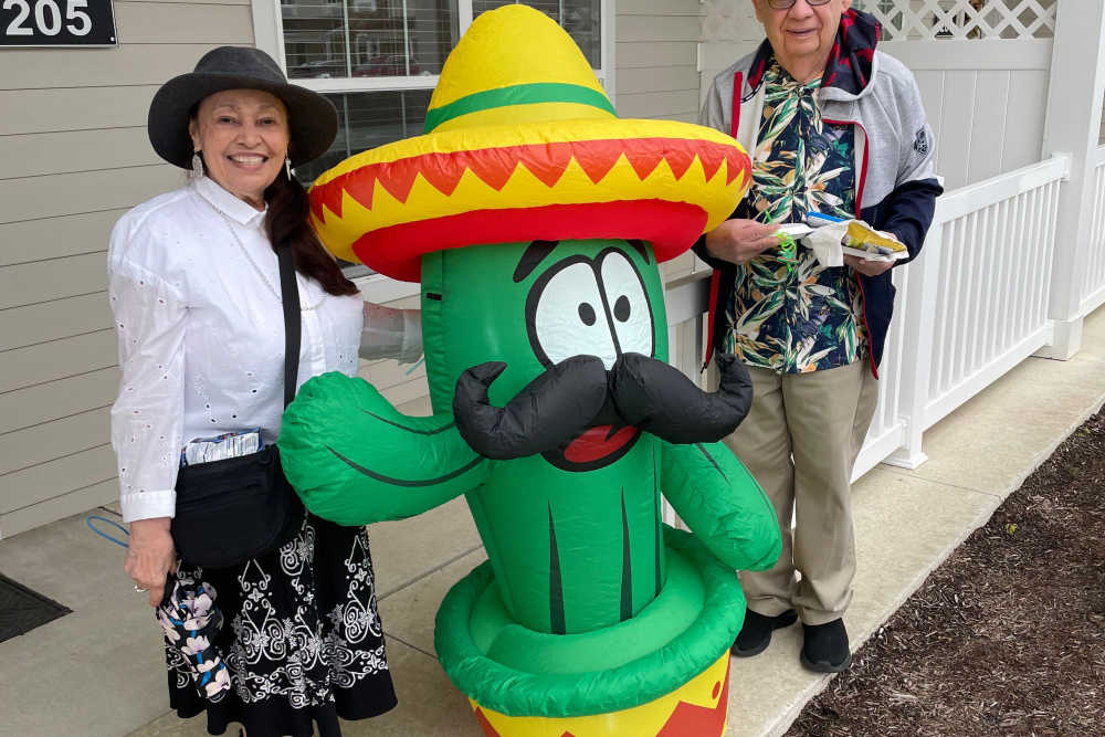 Two residents posing outdoors with a large inflatable cactus wearing a sombrero at Legacy Living Defiance in Defiance, Ohio  