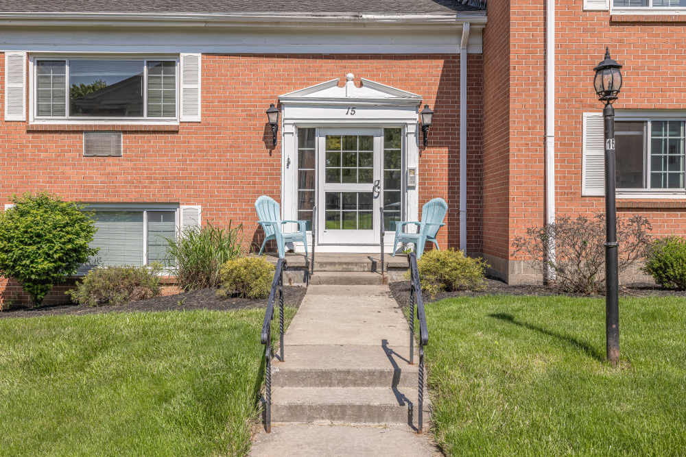 Apartment entrance with steps, railings, and seating at Pittsford Village Estates in Pittsford, New York