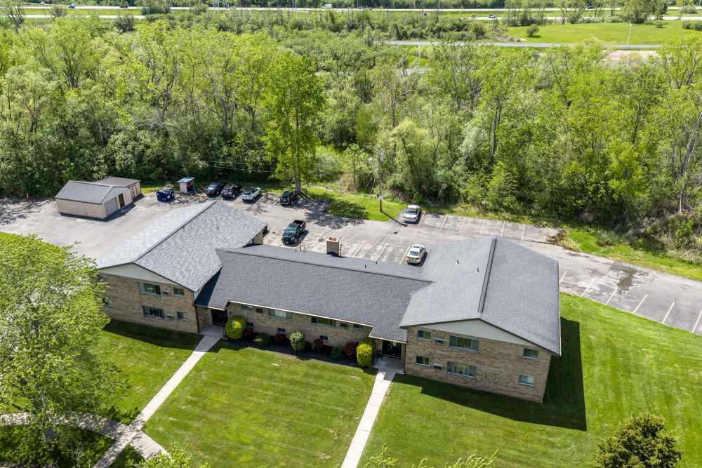 Aerial view of apartment buildings with parking area and tree-lined surroundings at White Oaks West in Gates, New York