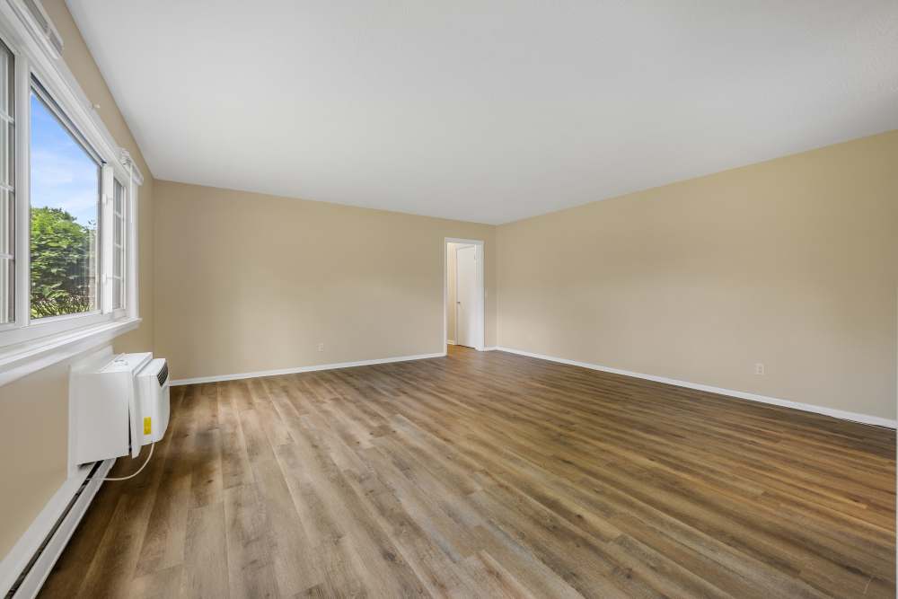 Bright bedroom with windows, carpet flooring, and wall AC unit at Pittsford Village Estates in Pittsford, New York