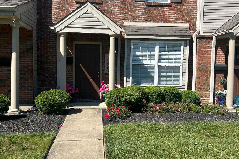 Front entrance with landscaped garden at Whispering Wind Apartments & Townhomes in Newtown, Ohio