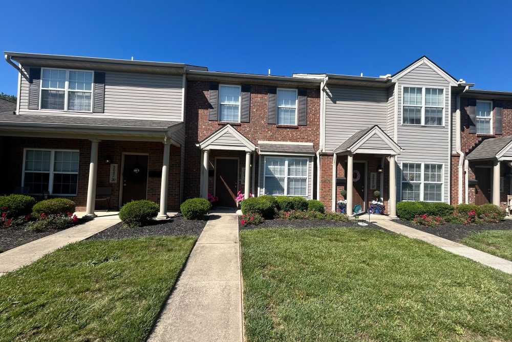 Townhouse exteriors with manicured lawns at Whispering Wind Apartments & Townhomes in Newtown, Ohio