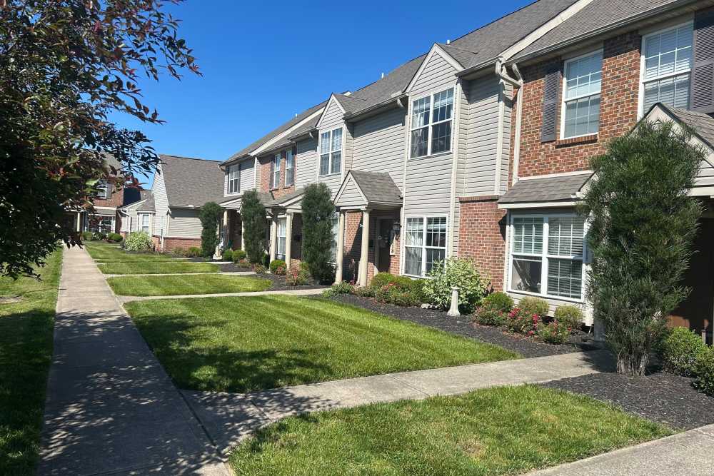 Townhouse exteriors with manicured lawns and walkways at Whispering Wind Apartments & Townhomes in Newtown, Ohio
