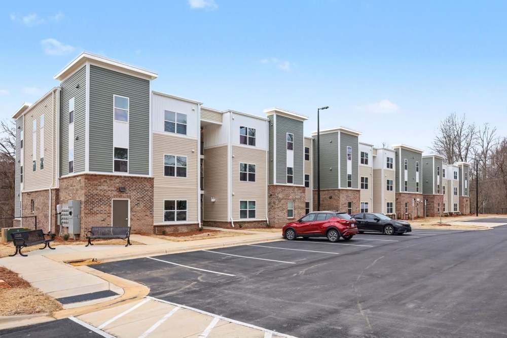 Modern apartment community featuring multiple buildings with ample parking and green space at Leonard Greene in Dallas, North Carolina