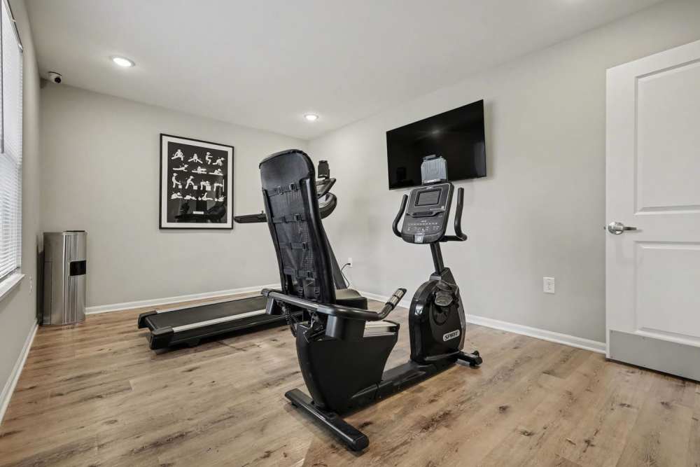 Modern fitness room with wood-style flooring, exercise equipment, and motivational artwork on the wall at Leonard Greene in Dallas, North Carolina