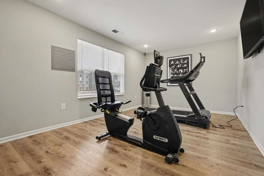 Fitness room featuring exercise equipment on wood-style flooring and natural light from large windows at Leonard Greene in Dallas, North Carolina