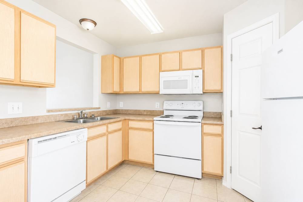 Kitchen with wood-style cabinets and appliances at Tuscany Court Townhomes in Hondo, Texas