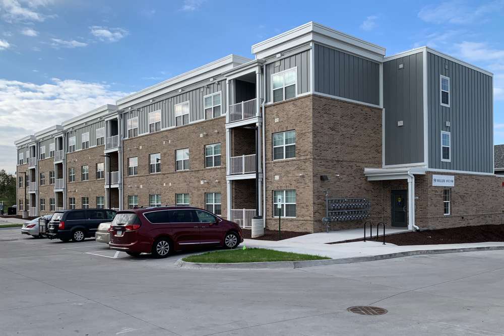 Modern apartment community with brick exterior, balconies, and landscaped parking area at Anderson Greene I in Cedar Rapids, Iowa