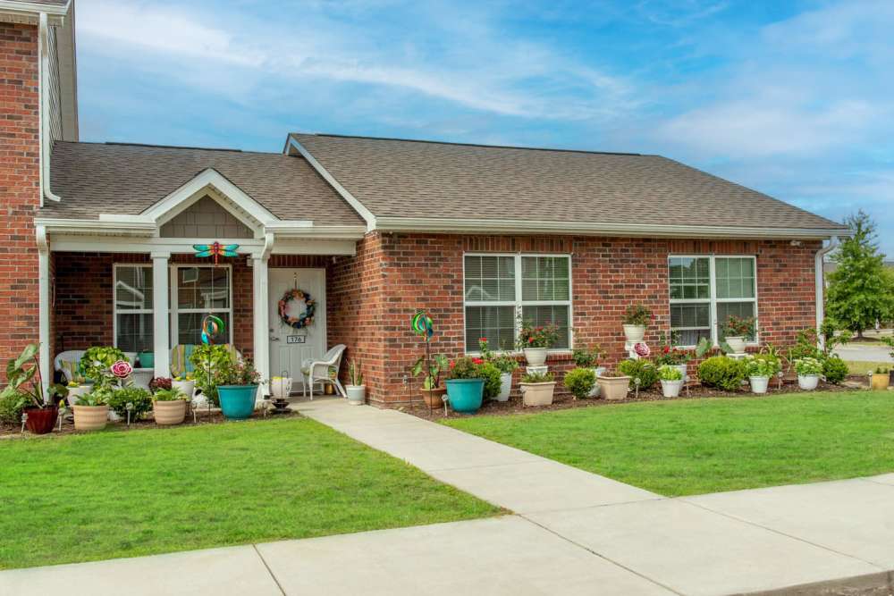 Charming brick apartment exterior with lush gardens and welcoming front porch furniture at Butler Crossing II in Kingstree, South Carolina