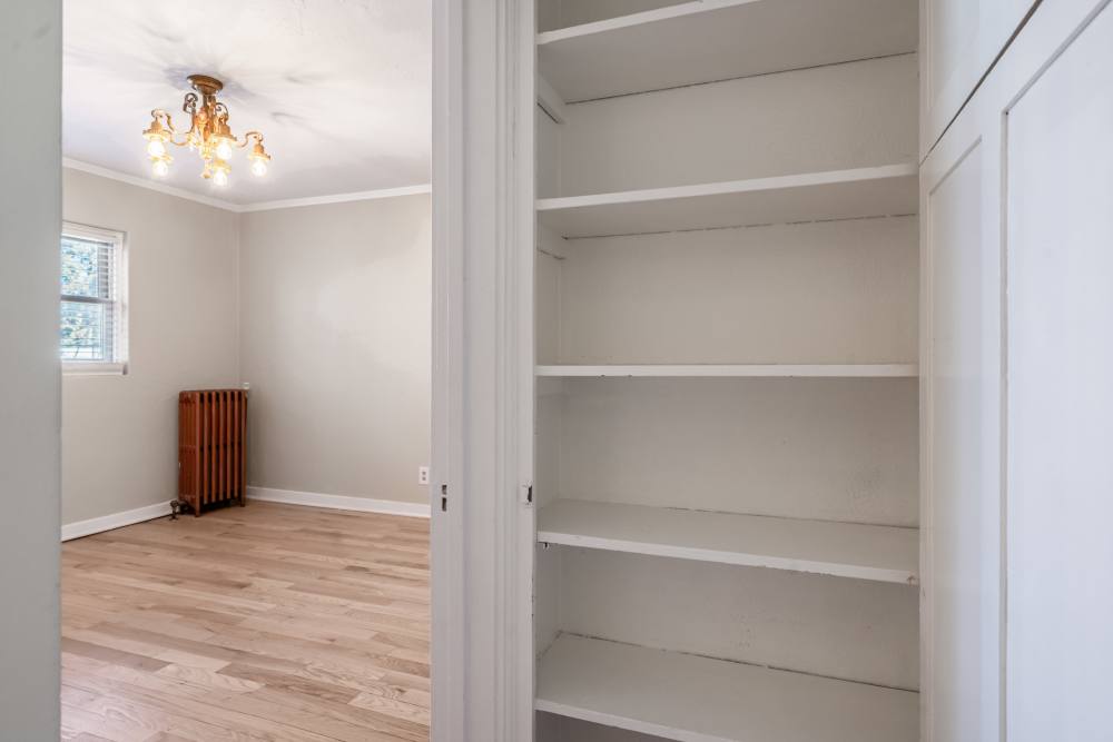Open shelving closet next to bedroom with wood floors and ceiling light fixture at Cascade Park in Colorado Springs, Colorado