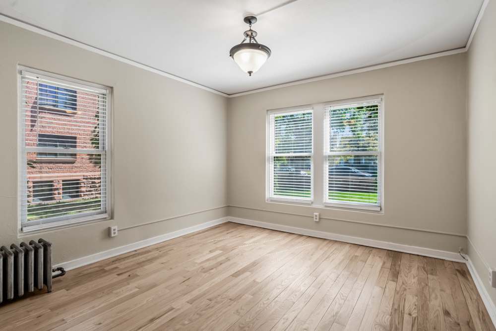 Empty living room with hardwood floors, radiator, and multiple doorways to adjacent rooms at Cascade Park in Colorado Springs, Colorado