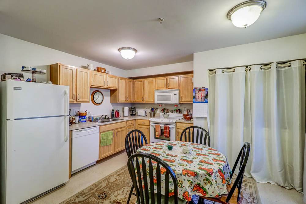 Cozy kitchen with wooden cabinets and dining table at Pinecrest Greene in Charleston, South Carolina