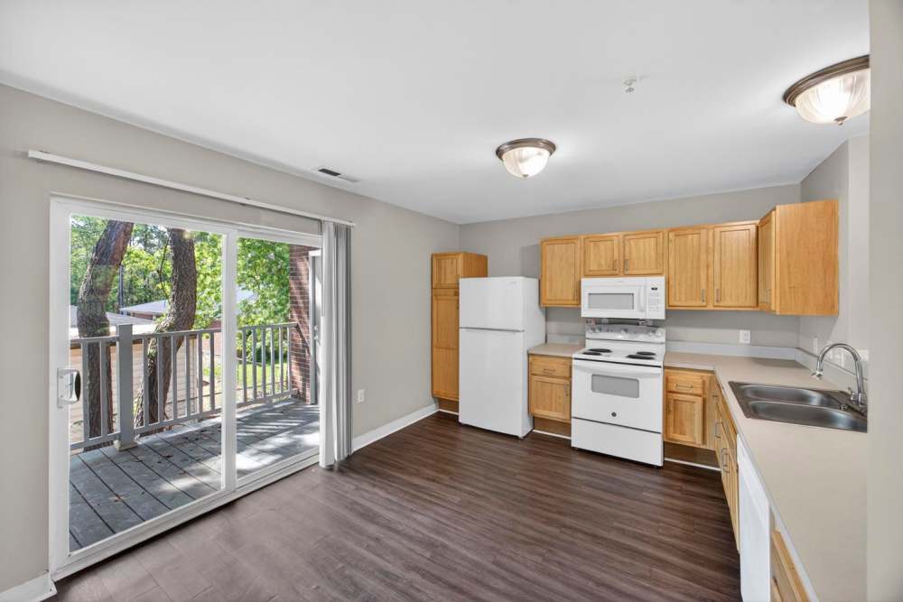 Bright kitchen with wood-style flooring and sliding door at Pinecrest Greene in Charleston, South Carolina