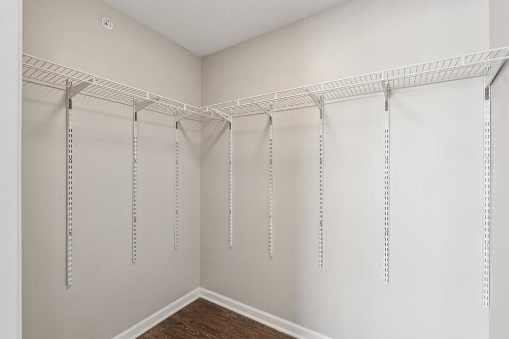 Spacious walk-in closet with wire shelving and wood-style flooring at Johnston Crossing II in Johnston, Iowa
