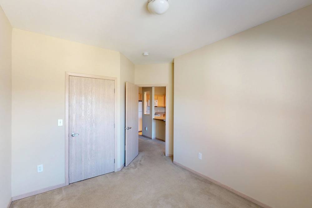 Spacious apartment entry with beige walls and carpet, leading to a kitchen area at Vine Street Lofts in Des Moines, Iowa