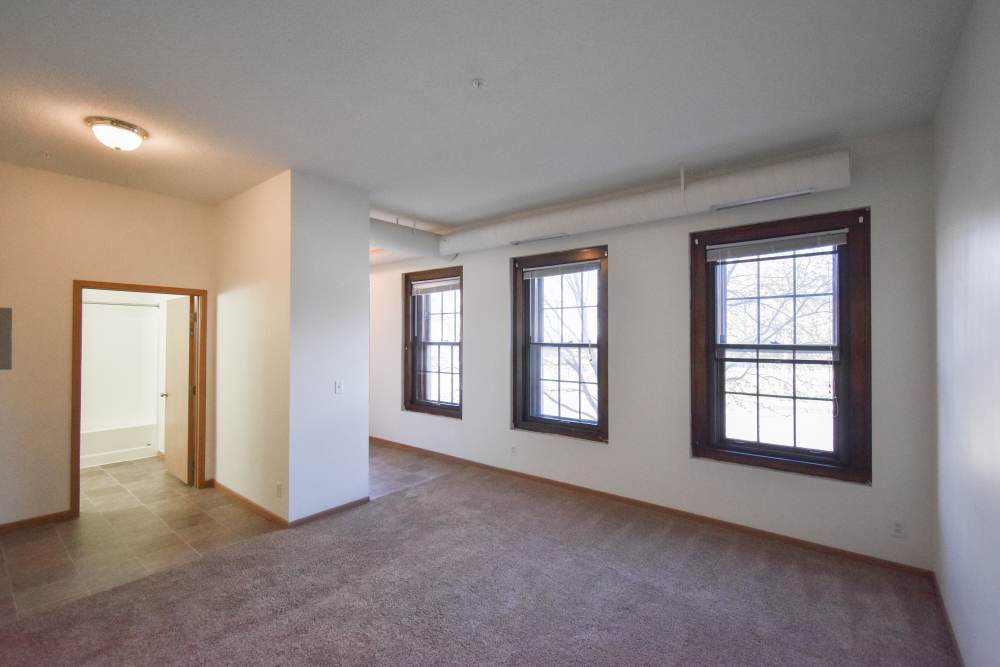 Spacious living area with large windows and carpeted at Bottineau Commons & Lofts in Minneapolis, Minnesota