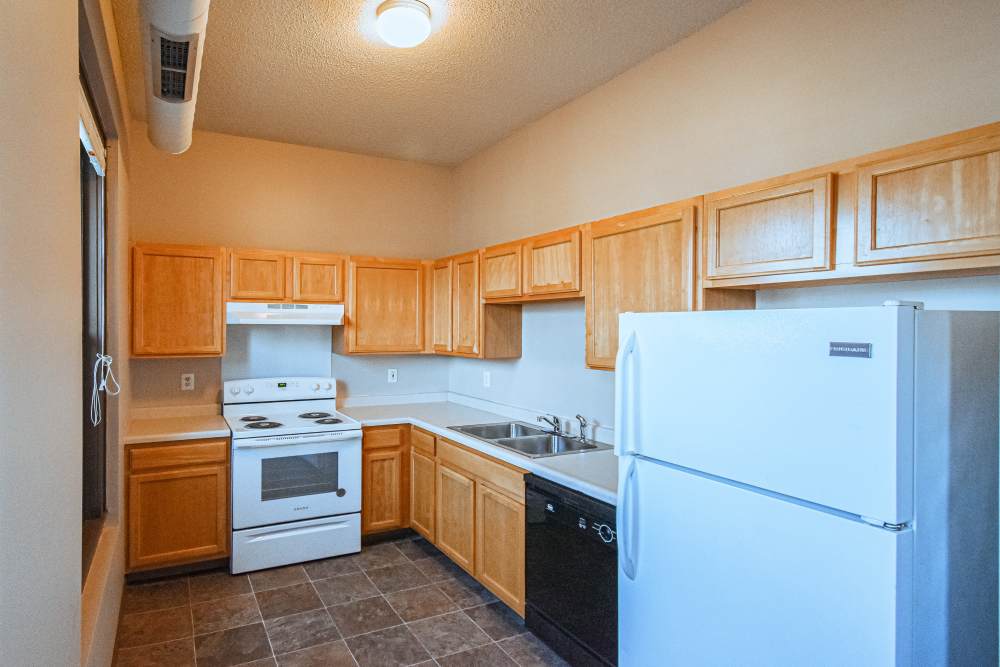 Bright kitchen with white appliances and wood cabinets at Bottineau Commons & Lofts in Minneapolis, Minnesota