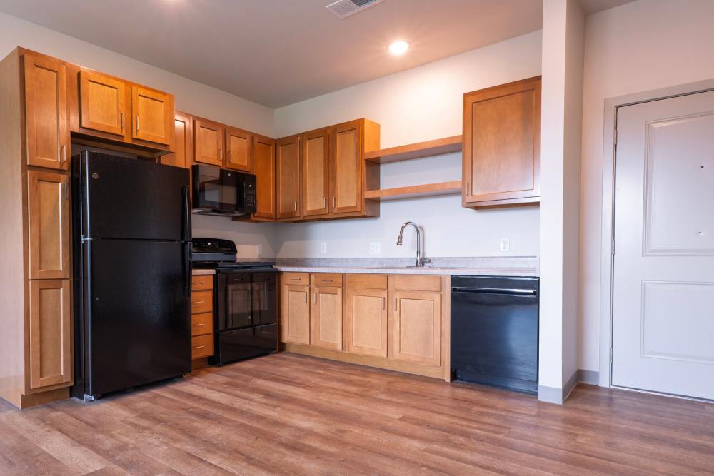 Kitchen with wood cabinets, black appliances, and open layout at Monarch Station in Louisville, Kentucky