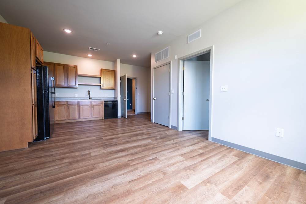 Open living area with kitchen, wood floors, and multiple doors at Monarch Station in Louisville, Kentucky